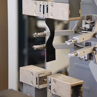 ISO 34-1: Bogenförmiger Probekörper eingespannt in einem pneumatischen Probehalter