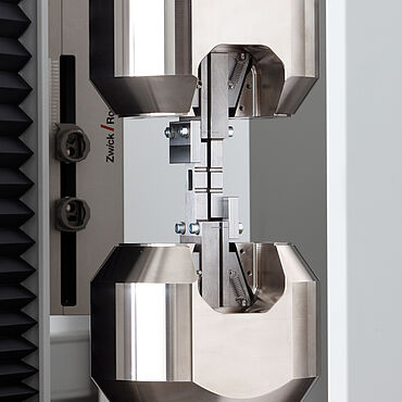 Testwerktuig voor open hole druktest volgens ASTM D6484 met antikniksteun in parallel sluitende hydraulische klemmen (afschuifbelasting of shear loading)