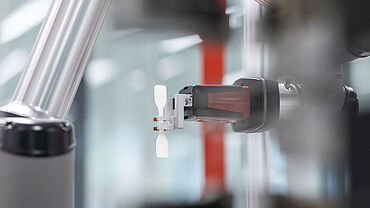Bei der automatischen Prüfung von Kunststoffen transportiert der Greifer des roboTest N die Kunststoffprobe