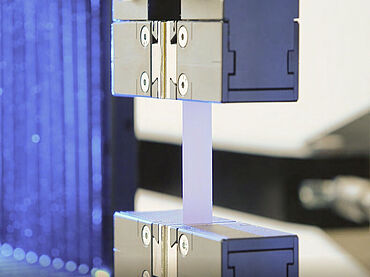 Detailaufnahme eines Zugversuchs an einer extrem dünnen Batteriefolie in der Lithium Ionen Batterie-Prüfung nach ASTM E345 und DIN 50154 - Zugversuch an Aluminiumfolie