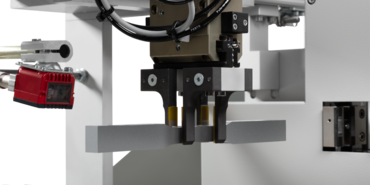 Роботизированная система 'roboTest L' гарантирует надежную транспортировку металлического образца к сканеру штрих-кодов, прибору для измерения поперечного сечения и испытательной машине.