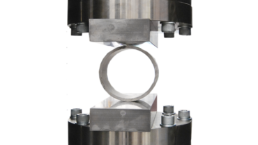 Beim Ringfaltversuch nach ISO 8492 wird ein Rohrring mithilfe von Druckplatten zusammengedrückt.