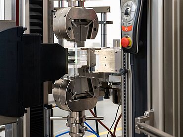 A laser extensometer with a short furnace enables strain measurement on flat specimens up to +1.400°C, which are gripped outside the furnace.