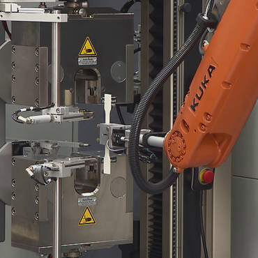 El sistema de ensayos automatizado 'roboTest R' transporta la probeta de plástico a la máquina de ensayos.
