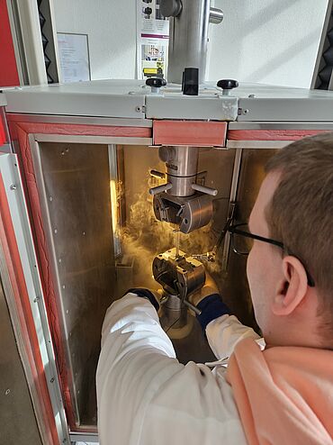Prüfaufbau für Zugversuche an Metallen in der geöffneten Temperierkammer