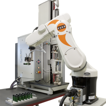 Der Roboter entnimmt einen Insulin-Pen aus dem Magazin und transportiert ihn sicher zur Prüfmaschine, wo ein Druckversuch kombiniert mit Torsion durchgeführt wird.