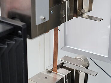 Detailaufnahme eines Zugversuchs an einer extrem dünnen Batteriefolie in der Lithium Ionen Batterie-Prüfung nach ASTM E345 und DIN 50154 - Zugversuch an Kupferfolie