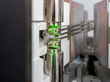 Zugversuch an Mikro-Proben unter Hochtemperatur: Detailaufnahme einer Minizugprobe in einer AllroundLine Prüfmaschine mit Hochtemperatur-Kurzofen bis 1.200°C und Laserextensometer laserXtens 1-32 HP/TZ