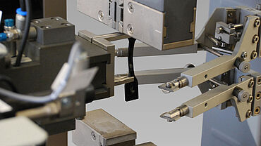 ASTM D412 - Uji tarik pada elastomer dan karet - tampilan detail spesimen halter elastomer, pegangan spesimen, dan ekstensometer